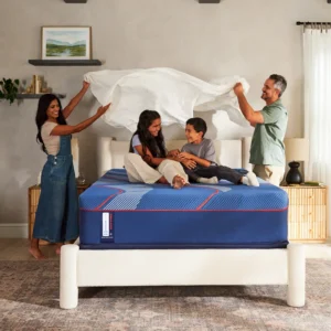 Family preparing a Sealy Brenham Soft Hybrid Mattress for use, featuring a blue mattress with red accents, in a cozy bedroom setting.