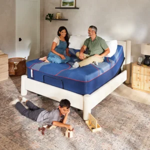 Family enjoying Sealy Brenham Hybrid mattress on a bed in a cozy bedroom setting, with a child playing on the floor.